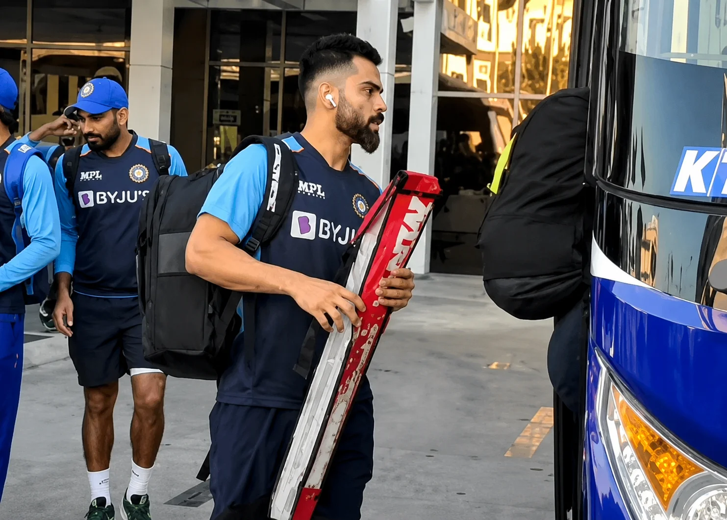Cricket squad in team kit boarding a KTC touring coach with bats and kit bags